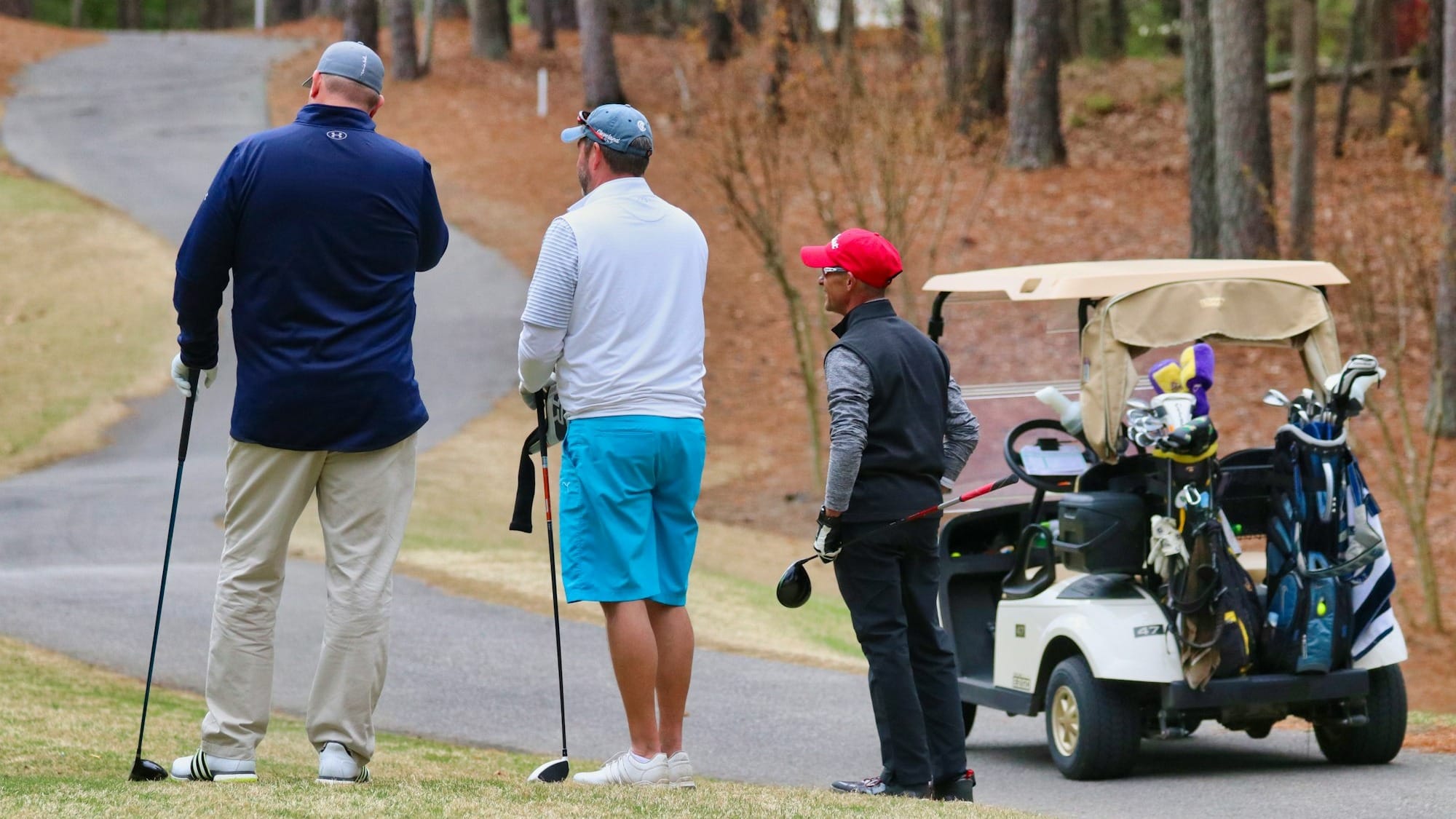 3 men in white uniform riding golf cart during daytime